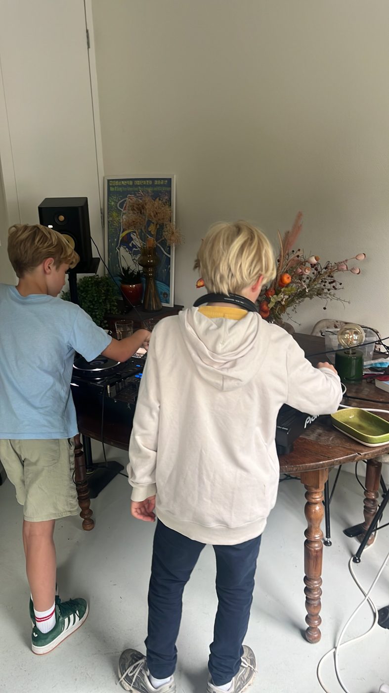 Twee jongens leren draaien tijdens een DJ les